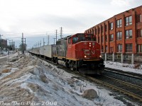 After a trip back from downtown Toronto, a stopover was made in downtown Brampton during the afternoon lull period, before the "GO rush" began. Afternoons on CN could be slow sometimes (maybe passed by a visit to "The Little Train Shoppe" across from the tracks, or Gusto's Pizza nearby), but one of the trains that did show up was the daily eastbound Roadrailer (CN train #144), that typically got a single 4- or 6-axle, often an older unit such as a GP40 or SD40 variant. The westbound counterpart (#145, except Friday as #147) was usually an evening train after the GO rush.<br><br>Today, we have CN GP40-2L(W) 9523 in faded CN North America paint leading eastbound Roadrailer train #144 through downtown Brampton. The 125 trailers following are busy hammering away at the CN-OBRY (ex-CP) diamond with the Owen Sound Spur, as 9523 is just about to pass Mill Street crossing and the nearby station. Snowbanks piled up along Railroad Street often provided a good vantage point, as this area was usually weeded out in the warmer months.<br><br>The last CN-NS Triple Crown Roadrailer trains would run in <a href=http://www.railpictures.ca/?attachment_id=21752><b>November 2015</b></a>.