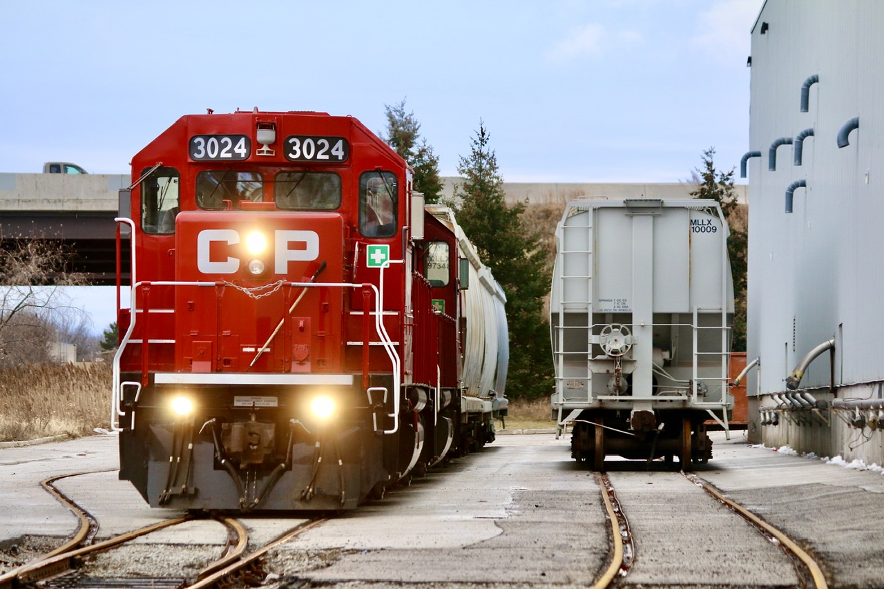And then there was one. There was originally two CP served customers on what still survives today of the old Owen Sound subdivision. A number of years ago the customer on the east side of the main that received boxcars downsized and later shared space with the customer on the west side of the main that receives covered hoppers. I believe the company was Katoen Natie as I don’t think the name is on the building anymore. It has been weeks since a boxcar has appeared at the north end and the unloading ramps have disappeared. Typically local H24 once a week will make the just over a mile trip to beyond highway 401 to service this last industry, passing a pair of long severed spurs along the way. This dreary day fresh looking GP38-2 3024 along with 3134 are seen working the service tracks at the last customer.
