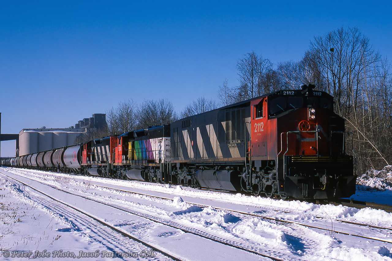 CN train 888 is seen getting its train together on the east side of Midland at Tiffin yards near Tiffin #2 elevator.  The three six-axle units, a BBD HR-616 and two GMD SD40-2Ws, will have easy work of the grain traffic out of the harbour, but will be put to work after lifting stone traffic from the Uhthoff Quarries.  Just over a year remains for grain traffic over the line, which once carried grain tonnage east to Lindsay and on to Belleville for points east.  The "at-and-east" grain subsidies cancelled in 1989 resulted in the closure of Tiffin (in 1989) and other lake great lakes elevators.  Note trailing unit CN 5334, the only unit painted into Expo '86 colours.Peter Jobe Photo, Jacob Patterson Collection.