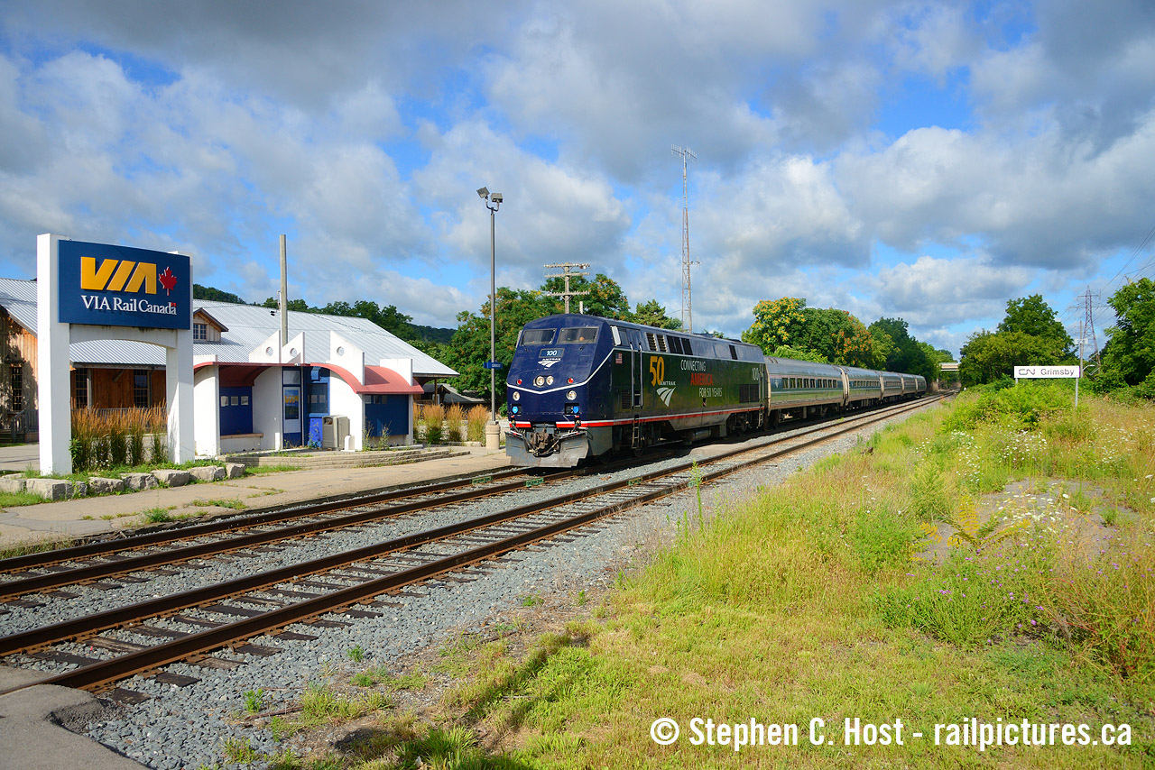 There have been four stations at Grimsby, and if I may, with all respect to Mr. Mooney and others who have been here too, I'm going to channel his photos posted here on here to illustrate. Pictured above is VIA 97 with Amtrak 100 which has just been flagged down by a passenger as this is now a 'flag stop'. Looking at all the clouds above me, it's kind of a miracle I got any sun at all, but the slow movement of the train helped. They would pull ahead a few more car lengths to let them on and I'd get back on the highway to 'tie' them to St. Catharines. But in this picture, there are two stations, the "2003?" built VIA over-designed shelter, and in the background is the original 1855 Great Western Railway station, restored, and it is my belief, this is the oldest wooden railway station left in the country. Happy to be proven wrong on that. Very few of these survived and the architecture of the Great Western's early stations, if you look at the photos of what was once in Toronto, seems quite unique, and this one still retains a large amount of that uniqueness if you have a look. The building was also recently for sale and restored by the most recent owners inside and out - I was able to tour it after restoration. (To be frank, it had its charm before restoration too as it was largely untouched with a few additions or changes inside otherwise).

In 1994 a fire burned the 1890 station. In the wake of that fire, VIA built what I recall is a makeshift square building with a couple benches/seats and a payphone, it was still there and moved to the side in the later 2000's before being removed or moved to the side for good. So that's basically it, there were four, only one is gone for good, possibly 2 if the VIA hut didn't survive (I believe it's nearby being used as a shed), and lets be honest, VIA's lame attempt at some over-designed red/white/blue shelter was a waste of money. But alas, people still call at Grimsby and the stop does get used, I was a customer to get to/from university when I still went home to see my parents, who live about 10 minutes from here. Other than this and Ingersoll, what else is a flag stop in this part of the country? Please comment below - corrections welcome as I may have dates a bit wrong.
