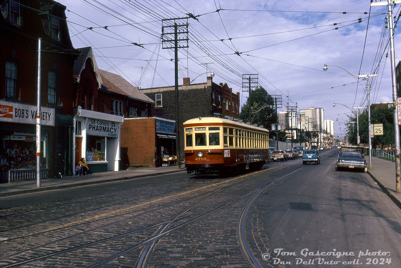 After restoration in 1973 for Tour Tram service downtown, the TTC's small group of Peter Witt streetcars (2424, 2766, and 2894) also became popular for fantrip charters. Here, TTC "small witt" 2766 is posed southbound on Parliament at Dundas. Unlike today, paving stones could still be found around streetcar intersections.

Present day, this strip along Parliament remains largely unchanged, and even Bob's Variety still exists at the same location (now as Bob's Convenience). 

Tom Gascoigne photo, Dan Dell'Unto collection slide.