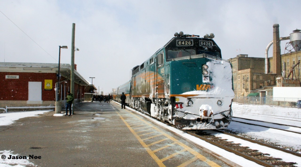 With obvious signs of battling snow drifts to the west, VIA Rail #84 with 6426 is viewed pausing to load a full platform of passengers at the Kitchener, Ontario station.