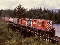 North of Wellington and at mileage 79.9, CP’s Victoria subdivision had a pile trestle bridge over an arm of Green Lake, and on Wednesday 1979-05-16, that was traversed by freight train No. 71 with GP9s CP 8502 and 8664 at 0941 PDT enroute Port Alberni.  The rooftop air reservoirs on 8502 indicate its origin as a steam generator equipped unit.

<p>Note the handy comparison of multimarks, original full-height on 8502 and newer smaller one on 8664.