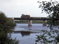 Canada and Gulf Terminal GMD SW8 102 (lettered for Chemin de Fer de Matane et du Golfe, CFMG) is heading westbound back to the yard at Mont Joli, seen here crossing the Mitis River at Price, Quebec.<br><br>Canada and Gulf Terminal (Chemin de Fer de Matane et du Golfe, CFMG) was a small regional 36 mile shortline that handled mainly paper and lumber traffic along the south shore of the St. Lawrence River, in the Mont-Joli to Matane area. Their small roster included GE 70-tonner 101, SW8 102, and SW1200 103 (acquired from the R&S), as well as an <a href=http://www.railpictures.ca/?attachment_id=23824><b>ex-NYC doodlebug</b></a>, and a combine used for mixed trains.<br><br>CN took over the line in 1975, and a <a href=http://www.railpictures.ca/?attachment_id=27905><b>ferry operation</b></a> was established between Matane and Baoie Comeau. One CN SW1200RS was even <a href=http://www.railpictures.ca/?attachment_id=26689><b>relettered for the CGT as 104</b></a>. CN ran operations until spinning the line off in 1999 to the Quebec Railway Corp (who ran operations with CFMG-lettered <a href=http://www.railpictures.ca/?attachment_id=42371><b>6900-series SD40-3's</b></a> and ex-CP RS18u's). When CN purchased a handful of QRC's operations in late 2008, it again re-acquired this portion of the line.<br><br>CFMG 102 was <a href=http://www.railpictures.ca/?attachment_id=22729><b>sold to Dofasco</b></a> as their 27/427 a few years later, and eventually became a slug.<br><br><i>Original photographer unknown, Dan Dell'Unto collection slide.</i>