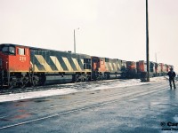 During an early winter snow squall, various units are seen crowding the CN MacMillan Yard diesel facility tracks in Vaughan, Ontario. HR-616 2111 with M-636 2322 await their next assignment along a set of local power that includes CN SW1200RM 7101. To the right, future railpictures.ca contributor Andy Gertz (with an Operations Exploration hardhat) looks on; no doubt ready to capture his next frame of Kodachrome 64.  