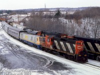 GP9 to the rescue! When an eastbound VIA passenger train lead by LRC 6911 ran out of fuel, CN sent out a locomotive to rescue the consist. CN GP9 4120 is seen leading VIA 6911 and its Toronto-bound train through Hamilton West on the Dundas Sub, passing an eastbound CN freight on the north track with a pair of M420's trailing.
<br><br>
<i>Bill McArthur photo, Dan Dell'Unto collection slide.</i>