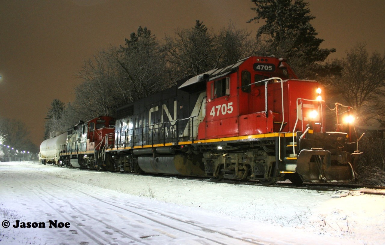 CN L566 with 4705 and 7025 wait patiently for a Siemens Canada worker to clear the sensors on the ION high and wide detector at Roger Street in Waterloo. Prior to L566’s arrival, an early evening snowfall had coated the area in a fresh blanket of white. Once the sensors were cleared by the worker, L566 was able to proceed north on the Waterloo Spur to the chemical companies in Elmira.