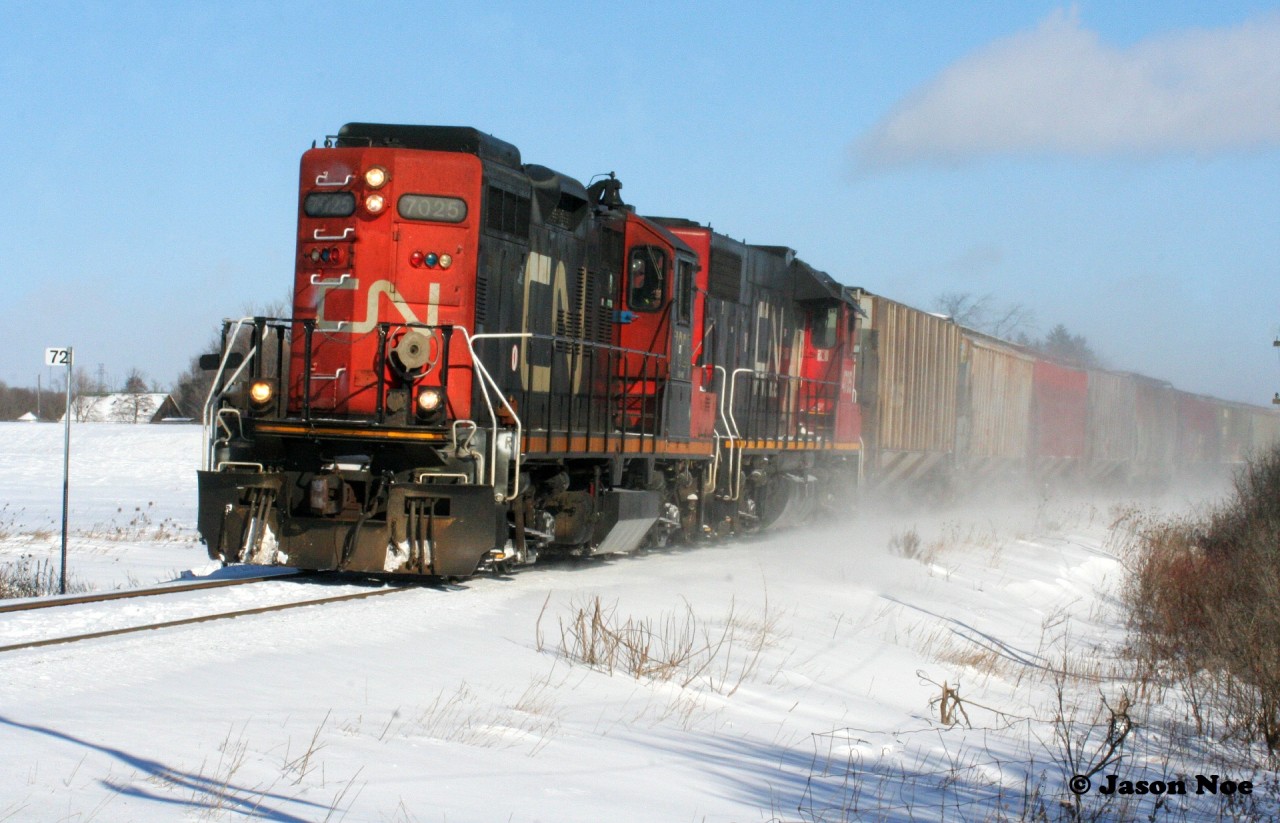 During a frigid February afternoon, CN L568 heads west to Stratford with GP9RM 7025 and GP38-2 4705 seen passing Mile 72 on the Guelph Subdivision in Baden, Ontario.