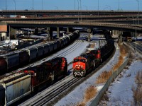 CN 543 at left (with CN 322's train) and CN 527 at right meet just west of the Turcot Interchange on a frosty afternoon. At left are parked grain cars.