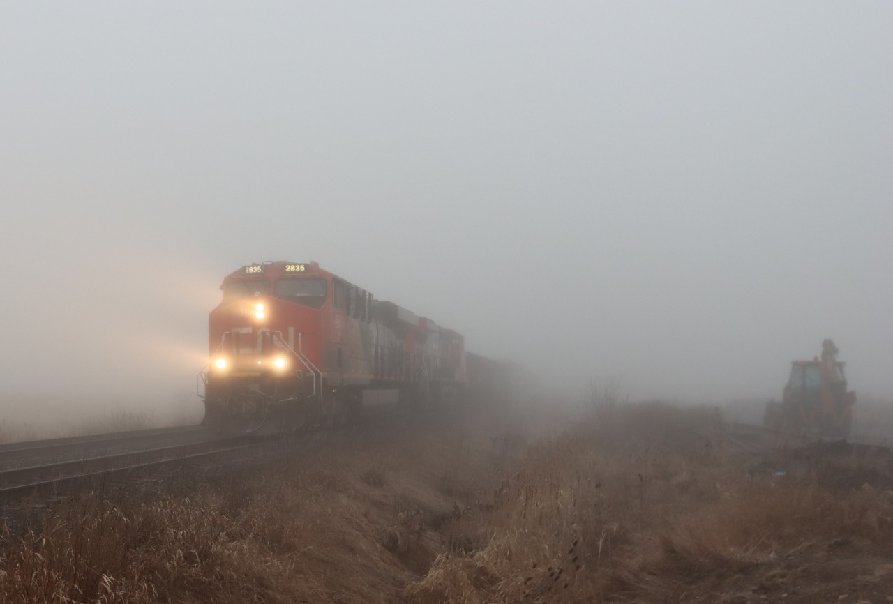 A421 emerges from the morning fog at Mile 42.0 Halton Sub.. A heavy fog blanketed the area this morning. The crews knowledge of the road is being put to the test this morning. Signals, signs, structures and other landmarks will be providing additional reference points for the crew in these reduced visibility conditions.   

A421 is operating a DP 2-1-0 configuration with CN 2835 CN 3332 and mid-train DPU CN 3232.
