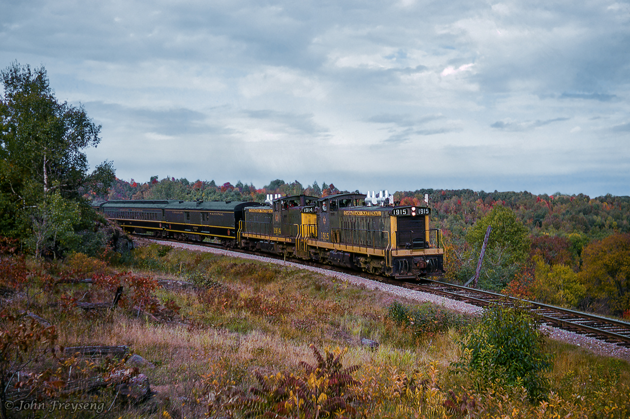 With extra flags near taut in the wind, CNR GMD1s 1915, 1914 round a curve near Burnt River during a runpast on the UCRS Toronto - Haliburton fall colour excursion of September 1963.  This pair of diesels took over at Lindsay for U-2-e class CNR 6167, hauling the excursion up to Haliburton, and return.  One of four runpasts held on that trip, another can be seen here at Kinmount.Scan and editing by Jacob Patterson.  [Note, geotagged location not exact.]