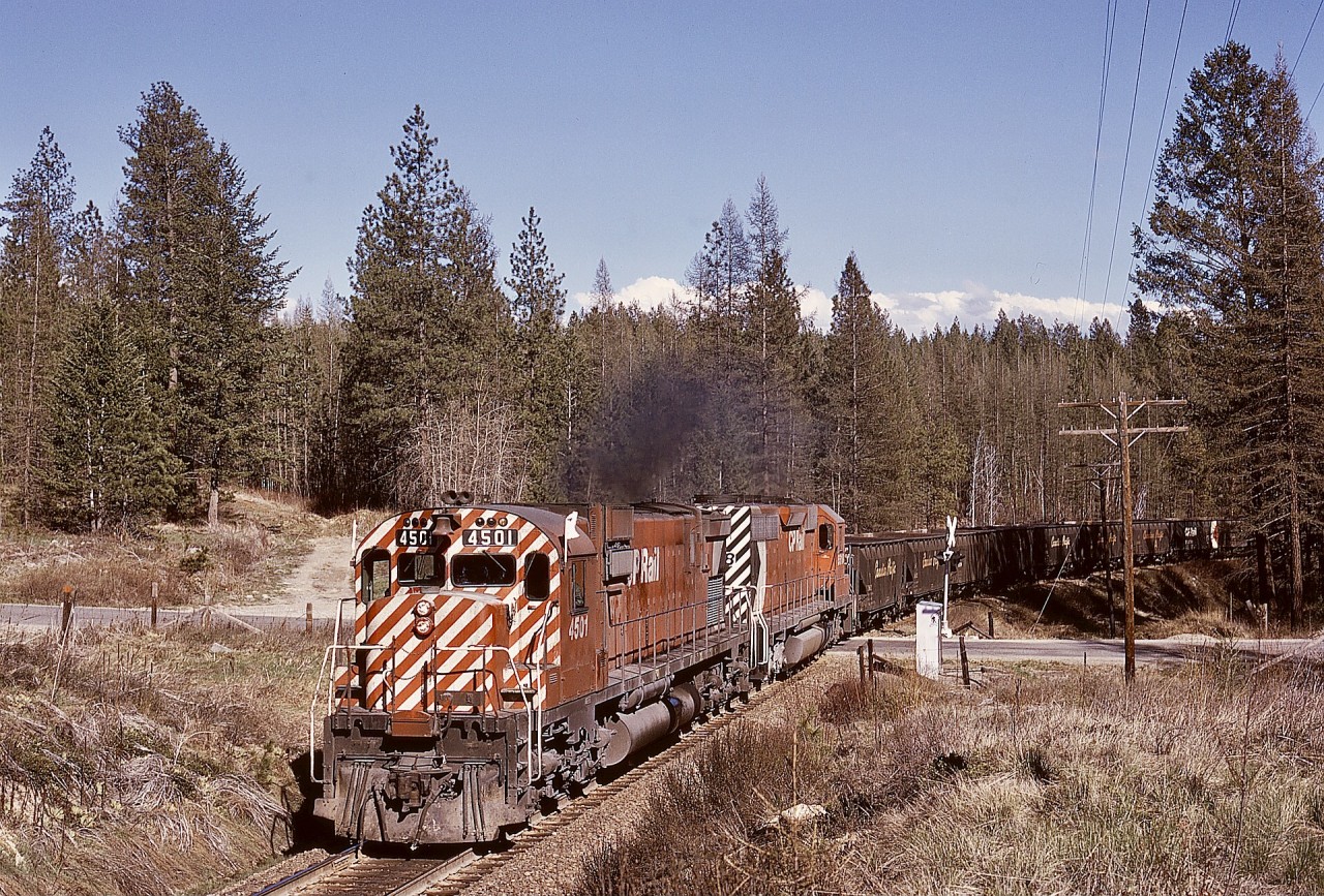 Northward from Cranbrook to Kimberley on what is now the Northstar Rail Trail used to be CP’s Kimberley subdivision, primarily to serve Cominco operations at Kimberley.  On my first solo road trip to the Kootenay region, a northward train of empties was followed from Cranbrook, with a big MLW, CP 4501, leading and a plain SD40, CP 5518, trailing, Nearing Kimberley, at a crossing of Knighton Road (mileage not recorded) in the area known as Chapman Camp, nearly 50 years ago on 1974-04-25, an everyday scene was caught, before SD40-2s in their increasing numbers took over in the west.