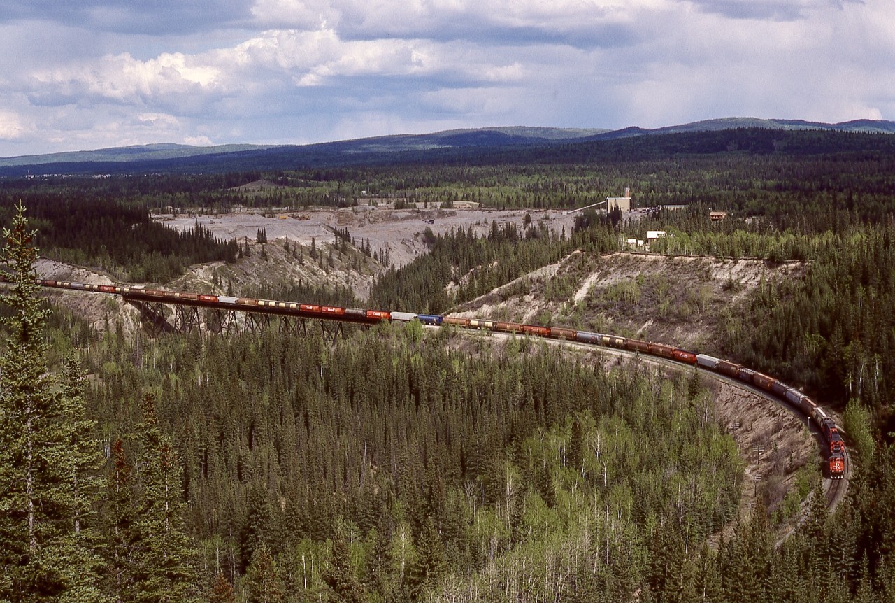 West of Hinton by about three miles, Maskuta Creek flows into the Athabasca River, and CN has a significant steel deck-plate-girder bridge to cross that creek.  On Saturday 1987-05-23, CN 5333 and two others hauled a grain train westward there enroute Jasper, with a large sand, gravel and concrete operation (no rail access) in the background.