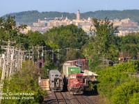 Smokin' Montreal Meet. On the afternoon of May 29, 2023, CPKC Canadian Pacific Train 112 with CP 8858 (ES44AC) as the outward facing DPU passes EXO Train 25, a Line 11/Vaudreuil bound 6-car train led by EXO 3003 at the Point-Claire Station in Montreal Quebec on warm afternoon of Monday, May 29, 2023. Some 10 miles (about 16 km) behind the trains in the background the 269 foot (82 meter) tall Roger-Gaudry Building at The University Of Montreal rises above the tree line. This is a great area to spend the rush hour as it is extremely busy for train traffic with EXO, VIA, CPKC, and CN all passing with good frequency.