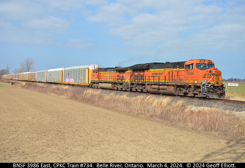 CPKC Train #734 rolls eastbound out of Belle River, Ontario with BNSF 3986 and 5477 on point for power.  As BNSF 3986 passes the westbound Belle River mileboard the Engineer throttles up and begins to pick up speed after pulling out of the siding where they had cleared up for a meet with train #231 on what was a beautiful, warm, sunny March 4th, 2024.