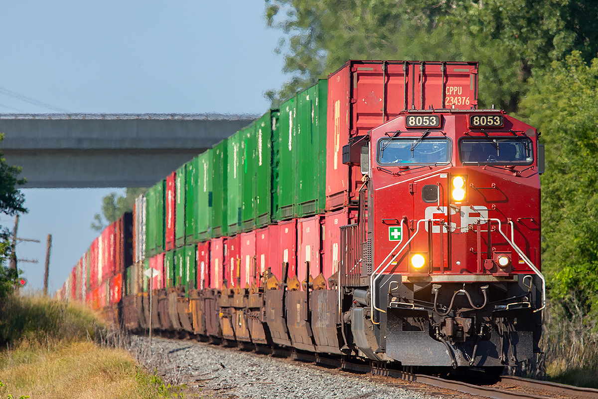 CP 8053 begins down the hill towards the Trent River which it will soon cross as it makes its way east on this sunny morning.