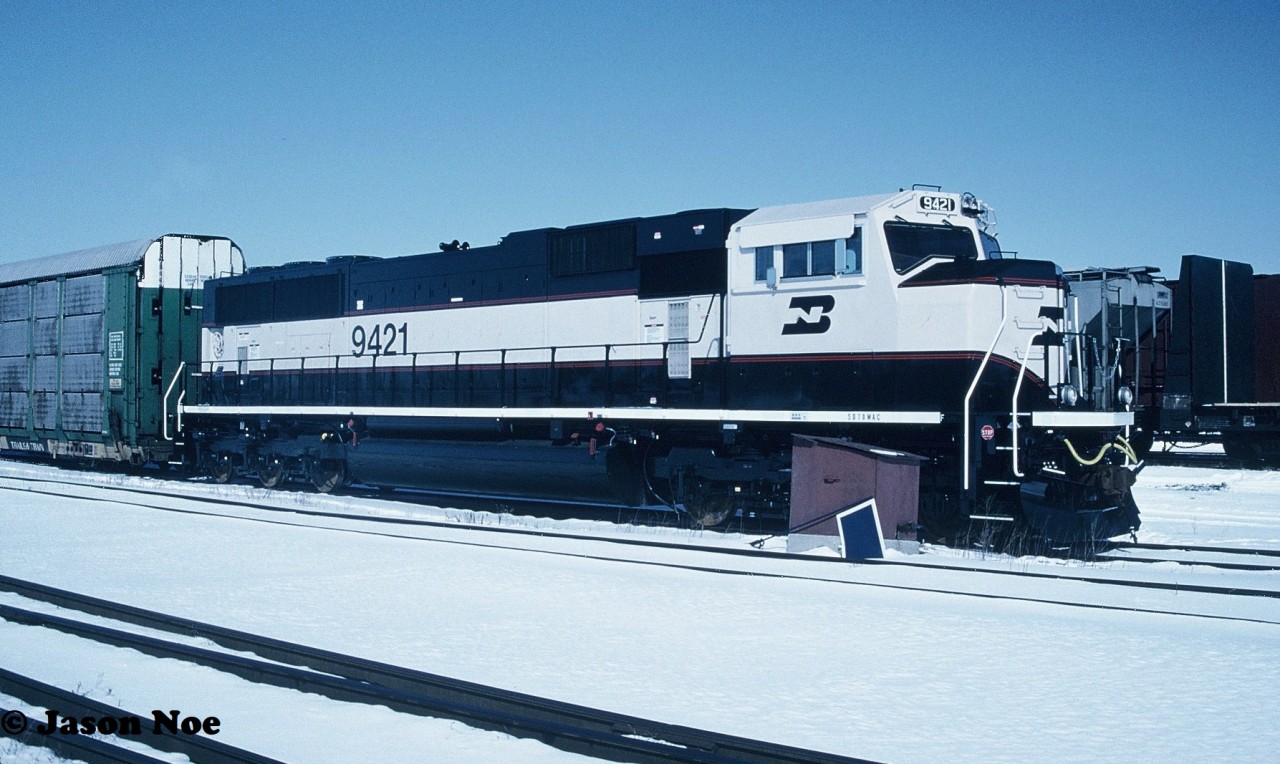 In 1993, Burlington Northern had placed a record setting 350-unit order with GMDD in London, Ontario for 4,000 horsepower SD70MAC’s totalling $675 million. In December 1993, the first one, BN 9400 rolled-off the assembly line at the London plant with 349 more to follow over the course of the next couple years. Painted in the BN “Executive Scheme” the units departed London for delivery to BN in Chicago via both CN and Canadian Pacific. 

Here BN 9421 gleams in the early morning winter sun at CN’s yard in London waiting to be lifted after having made the short trip from the GMDD plant.