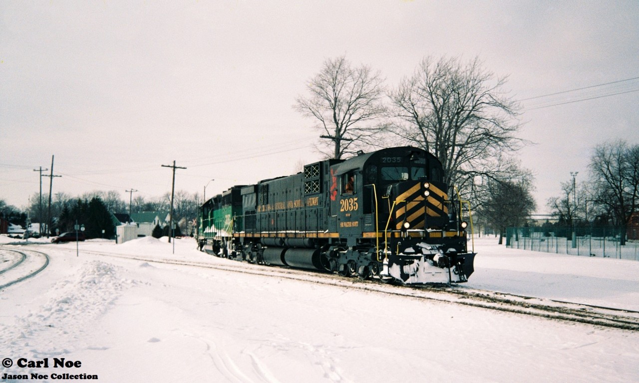Cape Breton & Central Nova Scotia Railway (CBNS) C630M 2035 and leased GATX GP40G 3080 bring a heavy Goderich-Exeter Railway (GEXR) train into Stratford, Ontario on February 6, 1994. The winter of 1993-1994 was a brutal one for GEXR’s fleet of second-hand GP9’s and by early February, most were either out of service or severely ailing. Cold winter weather and daily battles with squalls coming-off Lake Huron had proven too much for the veteran GP9’s, so RailTex turned to sister railway CBNS for help. The east coast shortline sent big MLW 2035 which operated between Stratford and Goderich for a couple weeks to help alleviate GEXR through their motive power crunch. In the end, 2035 would fare no better and would eventually be sent back east dead and in need of required repairs.