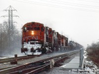 Dashing through the falling snow and kicking up a trail of the white stuff behind, CN M636 2316 leads a sister M636, a C630M, and some GP40 widecabs on train #432, heading timetable west on the Grimsby Sub bearing down on Battlefield Creek (near Lake Avenue North) in Stoney Creek.
<br><br>
An errant dog, possibly belonging to the photographer Bill McArthur (or another spectator present) heads the same way, likely wise or scared enough of the barking MLW and GMD power rapidly advancing to make a hasty retreat back to their owner.
<br><br>
<i>Bill McArthur photo, Dan Dell'Unto collection slide.</i>