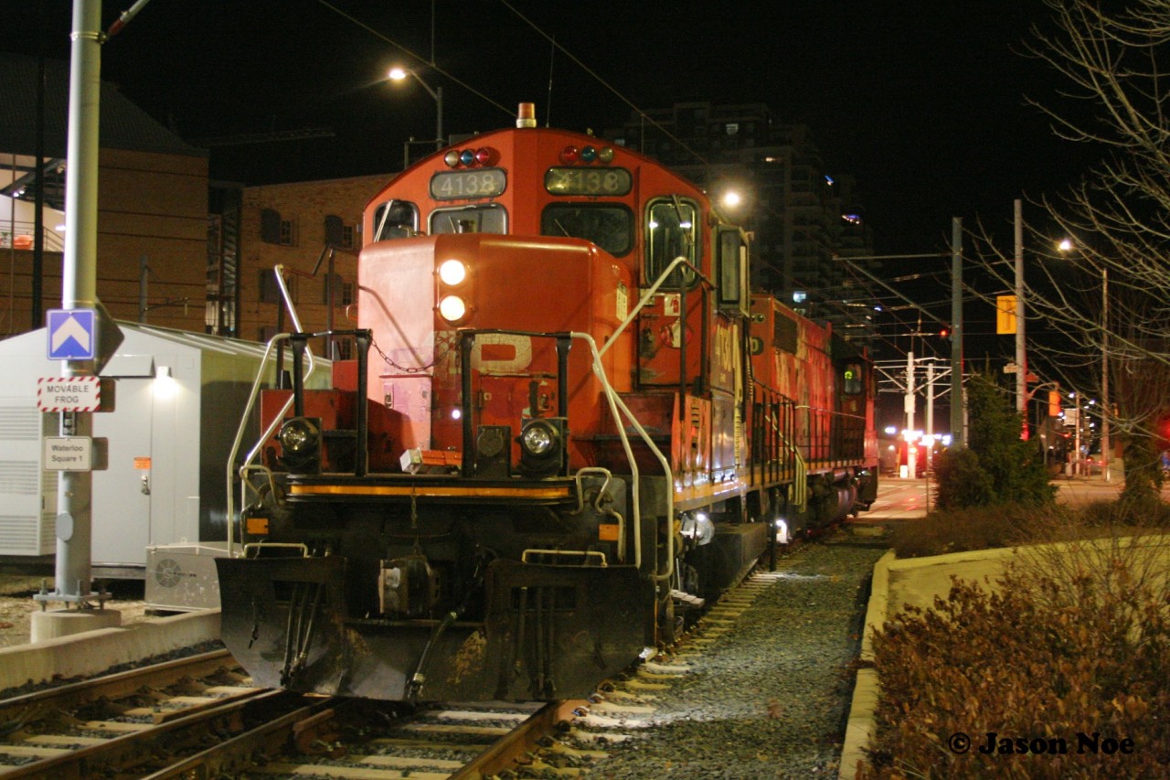 CN L566 pauses to cross Erb and Caroline Streets in downtown Waterloo, Ontario with GP38-2 4730 and GP9RM 4138. Once across the intersection, the local would continue its journey on the Waterloo Spur to Elmira with just light power.