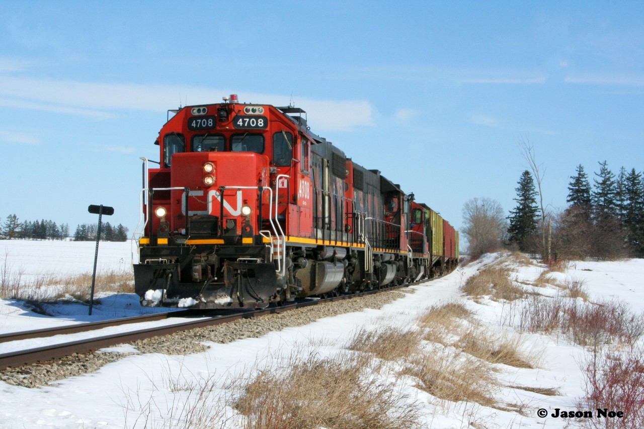 CN L568 with GP38-2's 4708 and 4710 along with GP9RM 7025 are viewed heading westbound to Stratford, Ontario, just west of the town of New Hamburg, approaching Road 102.