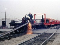 I'm not sure if I would be looking on if one was using a torch to cut the CW Rail without safety glasses but that's how it back in this 1977 photo. Here's a CNR CWR train laying rail at Chartwell street as the conductor looks on with his lunch box radio, waiting to pull the movement westward and to start dropping the rail clear of the crossing. Taken from my fathers collection.