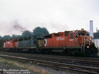 Some elephant-style second generation EMD/GMD action puts in an appearance on a gloomy day in Galt: CP Rail GP35 units 5021 and 5020 (in 5" striped <a href=http://www.railpictures.ca/?attachment_id=42072><b>"Ogden multimark"</b></a> and 8" striped large multimark paint schemes, respectively) splice borrowed Chesapeake & Ohio GP30 3004 on a westbound freight, rolling by the yard at Galt on the Galt Sub. White extra flags and nose class-lights lit up suggest this freight is likely running as "CP Extra 5021 West".<br><br><i>Bill McArthur photo, Dan Dell'Unto collection slide.</i>