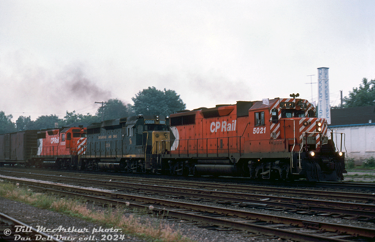 Some elephant-style second generation EMD/GMD action puts in an appearance on a gloomy day in Galt: CP Rail GP35 units 5021 and 5020 (in 5" striped and 8" striped large multimark paint schemes, respectively) splice borrowed Chesapeake & Ohio GP30 3004 on a westbound freight, rolling by the yard at Galt on the Galt Sub. White extra flags and nose class-lights lit up suggest this freight is likely running as "CP Extra 5021 West".

Bill McArthur photo, Dan Dell'Unto collection slide.