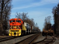 Repainted SD70MAC QGRY 4015 shoves on the rear of grain train QG 324 as it passes stored well cars in a siding. Three more SD70MACs are up front on this 16,000 ton train. 