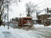 Not your regular Toronto streetcar: TTC Snow Sweeper S-30 plies its trade along the streets of Toronto, clearing snowy slush from Broadview Avenue near Wolfrey Avenue as a line of cars builds up behind.<br><br>Having a large streetcar network across the city, it was important to keep the tracks clear during winter weather. For decades, the TTC had its own fleet of snow-clearing equipment, including rail-mounted snow sweepers and snow plows (apparently they even had regular snow-clearing routes they were sent out on). TTC S-30, originally built for Taunton MA in 1920, and later serving on the Third Avenue Railway System of New York until 1947, was equipped with a set of motorized rotating sweeper brushes at both ends and side plow blades to push the snow back to the curb. Because of the bristles, the rotating brushes worked better than a standard plow blade to clear snow out of the flangeways of streetcar tracks. They were even used to couple up to and push stranded or disabled streetcars stuck in the snow.<br><br>The snow sweeper fleet was phased out by the early 70's, in favour of the city's own snow removal services. A few stored sweepers could still be found lingering around the back tracks of Roncesvalles Carhouse yard as late as 1973. Two units have been preserved: sweeper S-37 at the Halton County Radial Railway in Milton, and S-31 at the Seashore Trolley Museum in Maine.<br><br><i>Robert D. McMann photo (duplicate slide), Dan Dell'Unto collection slide.</i>