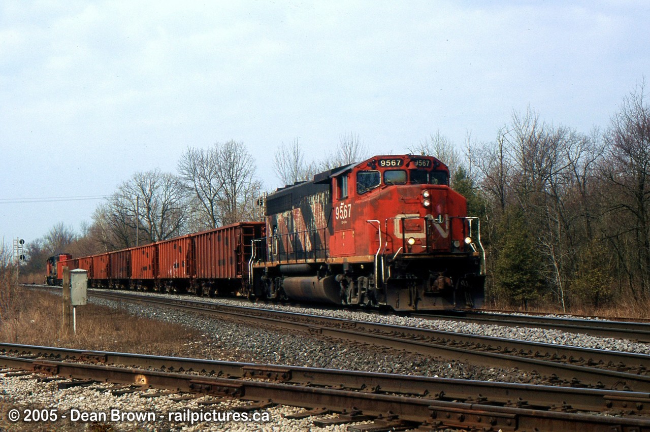 A CN Eastbound Ballast train with CN GP40-2(w) 9567 through Woodstock, ON as they approach the diamond of the OSR St. Thomas Sub that crosses the CN Dundas Sub back on April 6/2005.