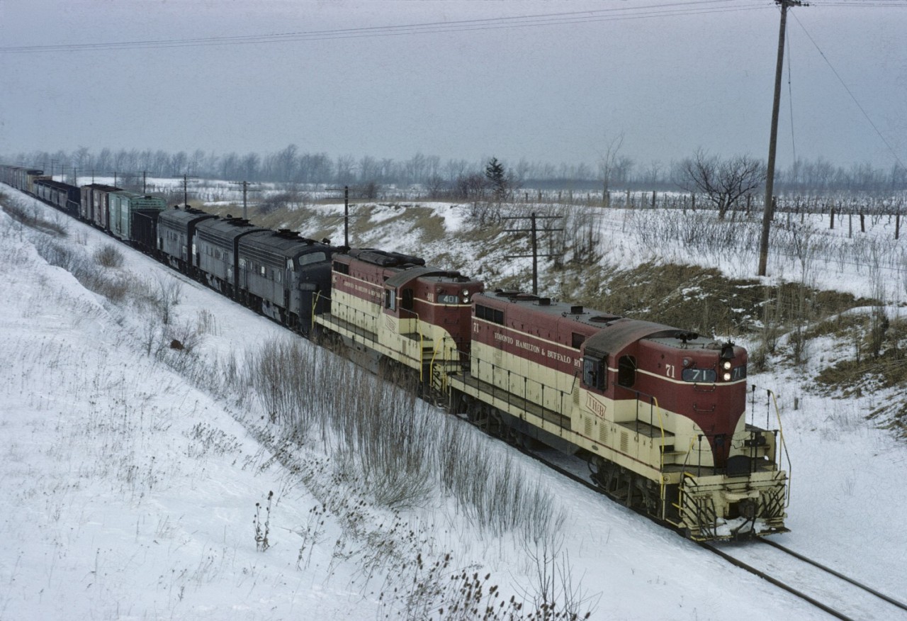 Fortunately TF2 is running late today and we can photograph TH&B 71 and 401 as they assist PC 1752, 1791 and 1773 up the grade into Vinemount in March 1972. 

The going-away shot can be found here:
https://www.railpictures.ca/upload/a-late-toronto-hamilton-buffalo-run-through-train-tf-2-crests-the-escarpment-at-vinemount-on-a-winters-day-in-march-1972-note-the-thb-puller-engines-a-gp7-and-a-gp9-assisting-the-through