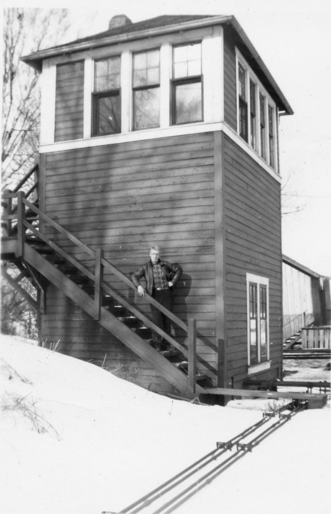 Signalman and Tower  
The Signalman stands on the stairs leading to the CPR Interlocking Tower at Mile 13.9 Milton Subdivision. CNR Interlocking Signals were controlled by the Signalman from this tower located on the south west quadrant of the Railway Crossing at Grade.