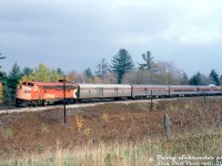 CP Rail FP7 4075 leads a short consist of #11 "The Canadian" (Toronto-Sudbury) around a curve northbound on the MacTier Sub near Medonte. A single F-unit was usually enough to handle the short #11/12 consists in the later years of CP operation, as the consists weren't very long off-peak (usually only having a Skyline dome, and no Park car. The Vancouver-Montreal #1/2 that met up with it featured a Park car). An old steel rounded-side baggage painted silver to match the previous livery trails the power, followed by a "bare bones" consist of a baggage-dorm, coach, Skyline dome, dining car, and possibly a sleeper or two (cut off).<br><br>The exact location of the train was not noted other than Medonte. It was shot from a road by a crossing (out of frame to the left). With the curve in the line it sort of seems like the crossing at Upper Big Chute Road south of Severn Falls, but it's hard to say for sure.<br><br><i>Barry Schroeder photo, Dan Dell'Unto collection slide.</i>