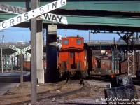 A wooden Canadian Pacific van (caboose) trails a short local freight job with a little Alco switcher in charge, pulling out of CP's Cherry Street yards and ducking under the <a href=http://www.railpictures.ca/?attachment_id=47272><b>Eastern Avenue</b></a> and Queen Street overpasses as it crosses over CN's Bala Sub onto CP's Don Branch. The van had just cleared Bayview Avenue, and is equipped with a trainline-operated air whistle on the rear handrail for whistling during reverse movements over crossings.
<br><br>
A sun symbol on the cupola is an odd touch, according to "Nicholas Morant's Canadian Pacific", this was an old practice dating back many years when crews used to fasten ornaments to their assigned vans to personalize them and make it easier to pick theirs out of a lineup on the van track.
<br><br>
Since the steam era, CP had freight sheds and team track facilities in the Cherry Street area to the east of Union Station, specifically north of the rail corridor between the Don River and Cherry Street (with spurs and sidings continuing west). CP's Don Branch (Belleville Sub) was on the east side of <a href=http://www.railpictures.ca/?attachment_id=33301><b>CN's Bala Sub</b></a>, so to access their own tracks CP would have to cross over CN first near Don. CP would also interchange cars here with CN at their own Cherry St. yards nearby.
<br><br>
In later years CP had a large freight shed here, but over time the largely industrial area fell into decline, and CP pulled up their Cherry Street industrial tracks around 1989-1991. The large shed would remain until most of the area was cleared out in the mid-2000's for a planned large-scale urban redevelopment of the formerly industrial West Donlands (today known as the Canary District).
<br><br>
<i>Keith Hansen photo, Dan Dell'Unto collection slide.</i>