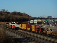 CN 401 has intermodal traffic and a string of TankTrain cars up front as it passes the rear end of a tied down CN B730.