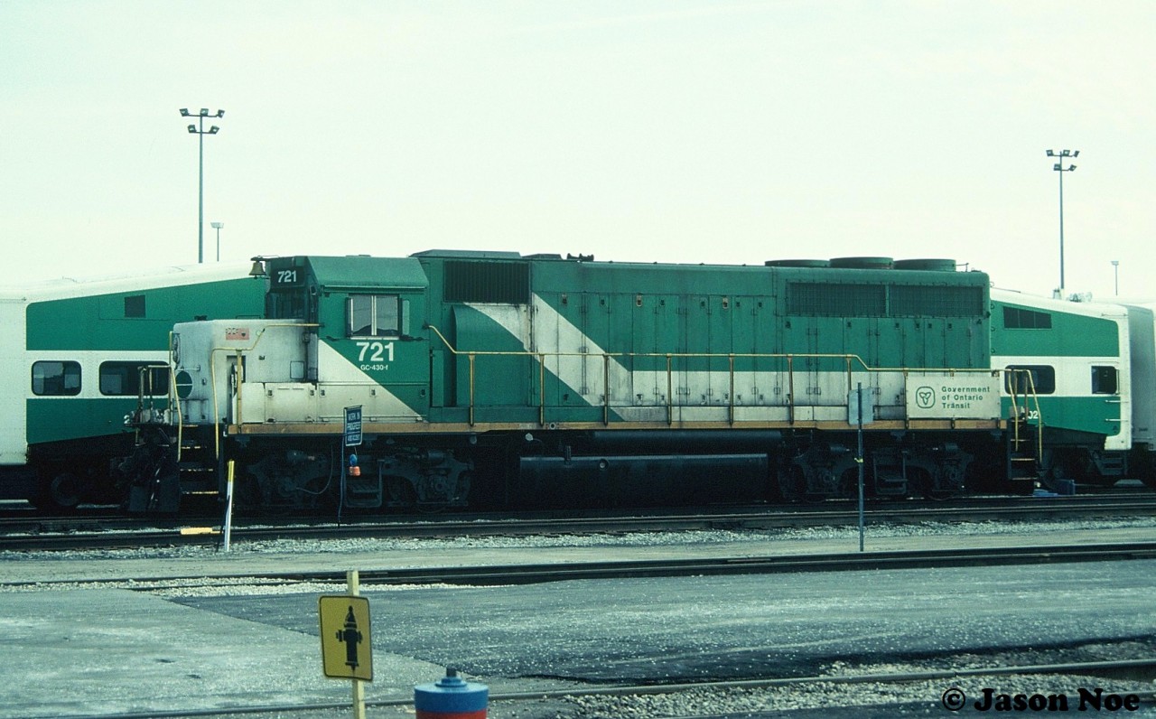 During an April afternoon, stored GO Transit GP40-M-2 721 is viewed at the Mimico, Ontario maintenance facility.  The unit began life as Chicago Rock Island & Pacific after being built by EMDD in January 1967. It was sold to GO in 1982 along with a group of other ex-CRI&P units. The GP40-M-2’s worked on the commuter agency for over the next decade until new GO F59PH’s eventually put them into storage and they were retired. On May 22, 1994, GO Transit 720-724 departed Toronto via CN for the VMV facility in Paducah, Kentucky where they would be rebuilt to EMD Leasing units. Sister GO units 725 and 726 were previously shipped to VMV in 1993 and had become EMD 200 and 201.