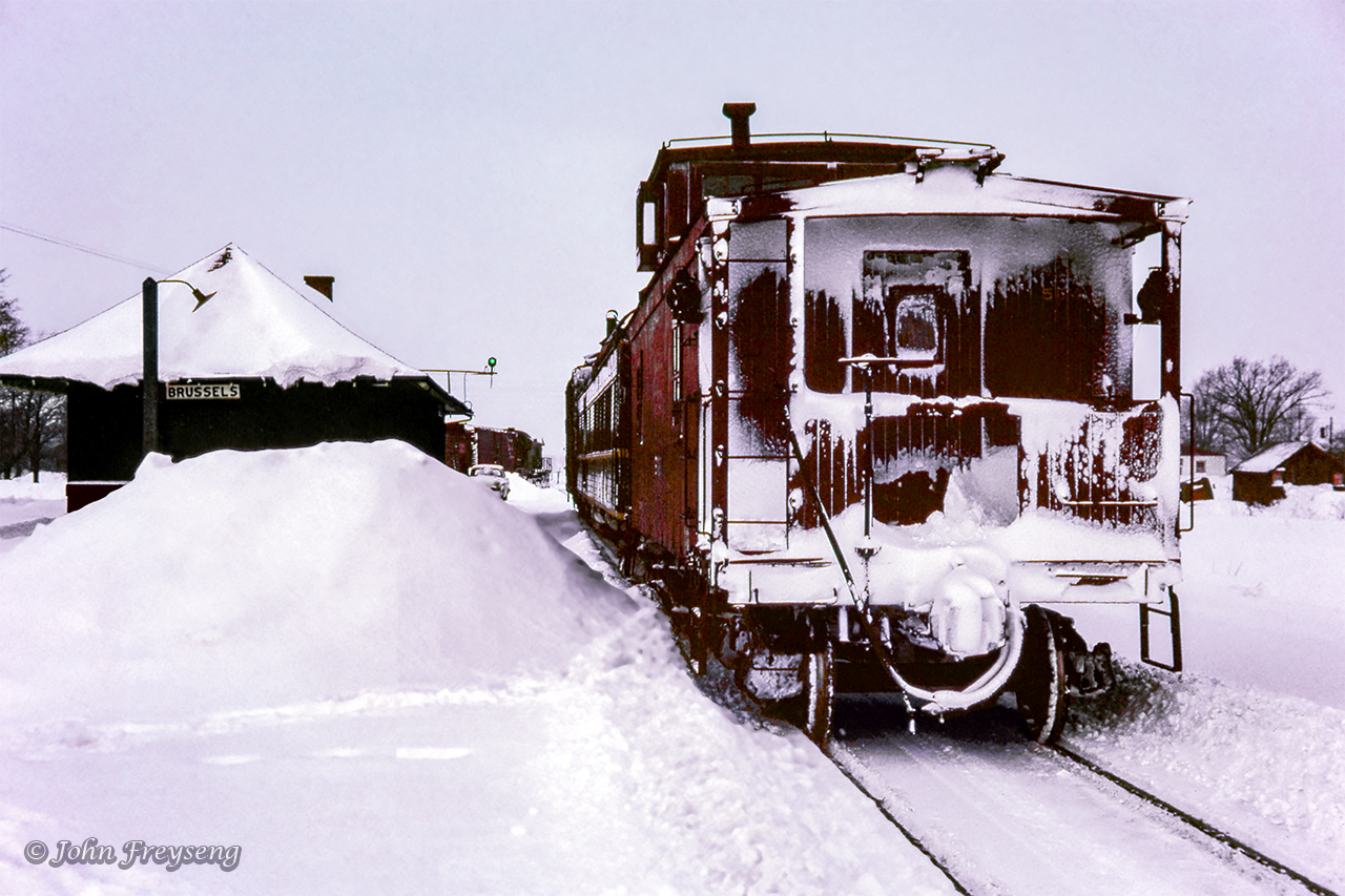 Several UCRS members made the trip to Palmerston on Boxing Day, 1962, to ride the wayfreight to Kincardine. The train, which ran as an extra, was not using a van for the tailend crew due to a shortage, but rather an old combine, giving the train the appearance of a mixed train. Regular passenger service on the Kincardine Sub still remained in 1962 in the form of one RDC trip. With releases signed, UCRS members were permitted to ride the "mixed," and with two at a time permitted to ride the flanger which departed for Listowel behind a pair of MLW RSC-13s; 1709 and 1732. While 1732 was the engine for the wayfreight, 1709 would be cutoff at Listowel to switch customers and prepare outbound cars for other train, returning light to Palmerston and over to Durham for other work later. Bringing upthe rear of extra 1732 was flanger CNR 56466, clearing some lake effect snow that had been accumulating between the rails.

Here, CNR 1732 can be seen setting off two stock cars beyond Brussels station. These will be lifted on the return trip a few hours later, and will be left at Listowel to be picked up by the Stratford wayfreight. Built by the Grand Trunk in 1899, the station, minus the freight section, has since been preserved as 212 Turnberry Street as the local lawn bowling clubhouse.

Further details can be found in the February 1963 UCRS newsletter.

Scan and editing by Jacob Patterson.