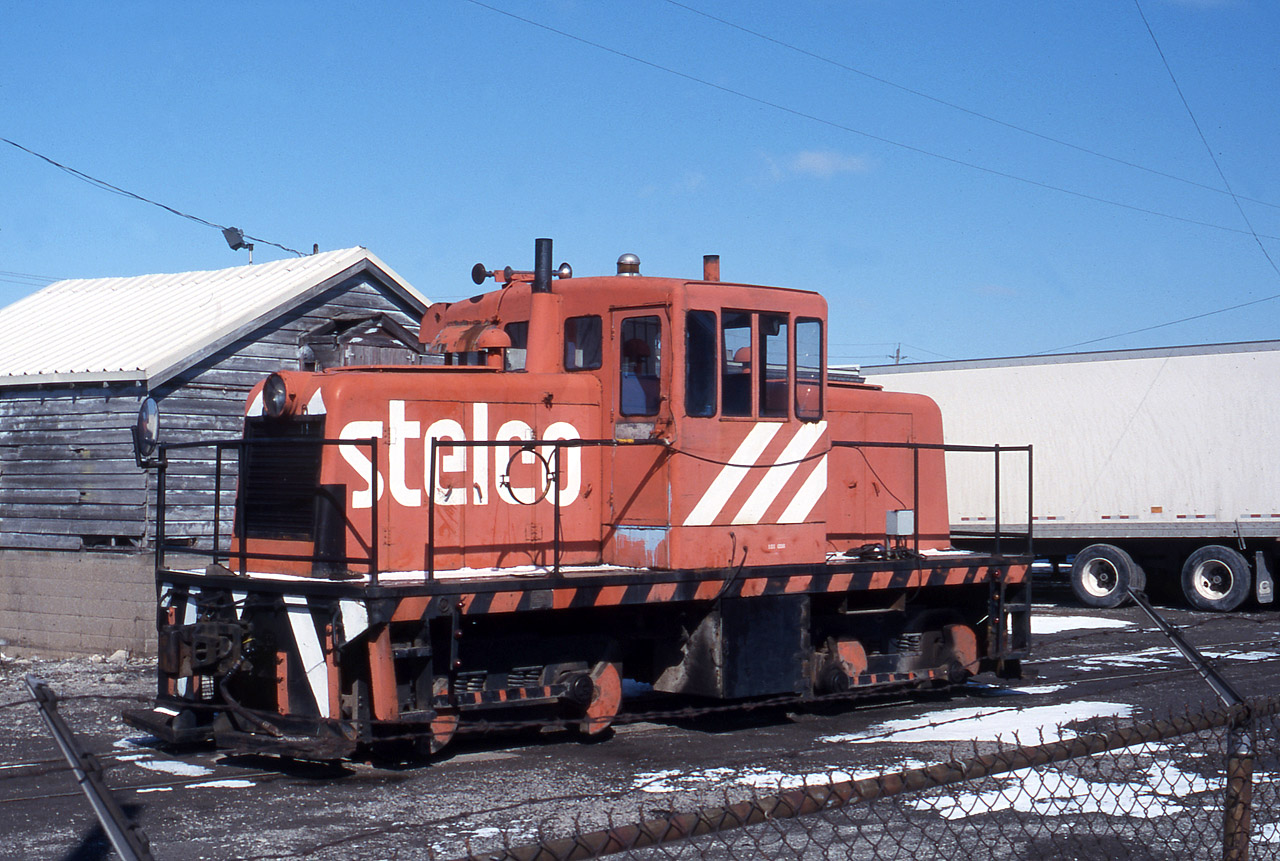 In 1997 ADM (Archer Daniels Midland) purchased the Maple Leaf Mills, which included the Port Colborne operation.  ADM and the MLM previous owner have a history of "on-again / off-again" in-house critters for switching.  When nearby STELCO Welland (Page Hersery and Welland Tubes) closed around the time this photo was taken, ADM picked up one of the GE Center Cabs for an "on-again" stint.  This was likely short-lived, and not sure the unit was ever re-painted out of the STELCO livery.  Trillium tried a few years ago to station at GE Center Cab at this location, but that unit was eventually moved to the PSTR in Port Stanley, ON.  GIO did have a SW 7920 on duty there for most of the recent winter, but that ADM seasonal work ended in early March 2024. Thanks to Steve H for the image clean-up