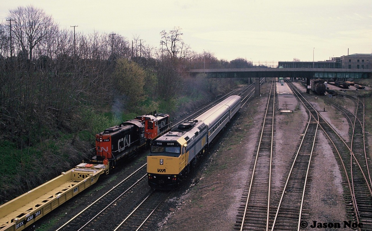 During a slightly overcast spring morning, VIA Rail train 92 powered by 6428 passes a CN job switching Stuart Street Yard in Hamilton on the Grimsby Subdivision. CN 1355 and 7101 were sorting newly built DTTX container cars manufactured at the nearby National Steel Car facility.