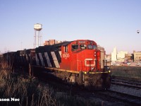 During a spring evening after completing their work, CN 421’s crew had to wait for the 15:30 Kitchener Job to return to the yard with their lift of newly built automotive frames from the Budd plant in Kitchener. Knowing they had some ample time to wait, they departed the yard light power down the siding towards King Street for some dinner options. The units included; CN GP40-2L(W) 9505, C-630M 2038 and an SD40-2(W). The power crossed King Street and stopped behind the plaza, that featured a Tim Hortons, Subway and a McDonalds across the street. At the time the siding extended even further west towards Park Street, however this portion was rarely used as most trains exited it at King Street through the cross-overs. 
<br>
So pictured here is 421’s power in the siding with the iconic Epton factory and its water tower in the background. Also, several other factories can be observed, showing-off Kitchener’s once vibrant industrial past. To the right of 9505 is the Guelph Subdivision mainline with another small siding track and the very far track is the Huron Park Spur. Today this is the location of the GO Transit layover facility and the plaza where the crew went that night is completely gone. 
