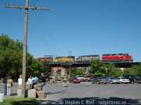 Visitors to an open house at WC Woods in Guelph mull around while a photographer for the Guelph Mercury in the vest looks at the train passing overhead. Hauling a d9r dimensional from Babcock and Wilcox (now BWXT) in Galt, this Extra 432 is heading east out of Guelph passing over downtown Guelph on a viaduct bridge built in the 1850's. This was the 'rainbow' era of GEXR where about 11-12 four axle units were all they had and big trains to/from Toronto with this classic power was a daily activity. The train is partially framed in the GJR 'telltale' that was located here until around 2019 when it was unceremoniously removed. This site has pretty much turned into condos now and will soon be a 5th building located where I am standing or thereabouts. 