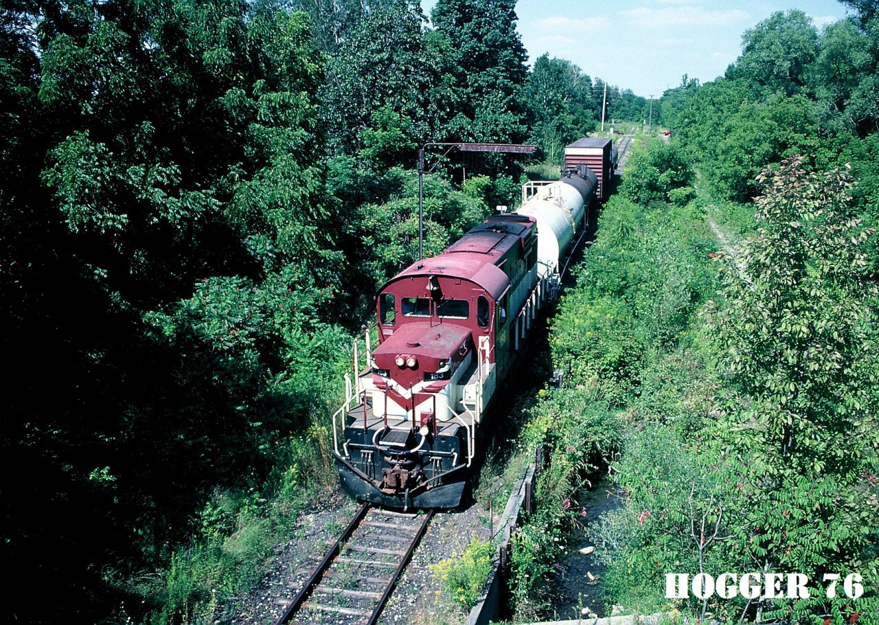 Ontario Southland Railway RS18 183 south arrives in Tillsonburg, Ontario with a small train from the CP interchange at Ingersoll. The train is going under the classic “telltail” on the Tillsonburg Spur (former CP Port Burwell Subdivision). Built with a low nose in 1968, RS18 183 is ex-INCO 208-3. The view was from the now abandoned Caso Subdivision, which crossed over both the CP Port Burwell Subdivision and CN Burford Subdivision at this location.