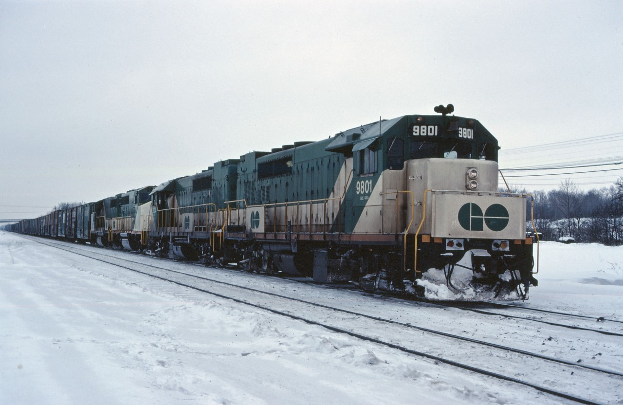 On one of those dreary southern Ontario winter days, a CN freight eases past the old cold storage building at Aldershot and prepares to work Aldershot yard. CN is still leasing GO Transit power on weekends, with a pair of GP40TCs and GP40-2LWs powering this eastbound. More GP40-2Ws and M420Ws are due from GMD and MLW later this year, which will soon make such scenes much less common.