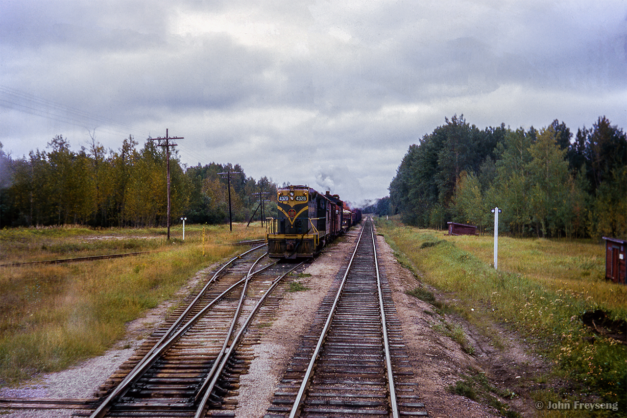 A westbound work train sits in the siding at Smooth Rock, ON, behind GMD GP9 4329. Note the steam escaping from the stack of a crane in the consist.  At left, the Mattagami Railroad's line running roughly 3 miles north to Smooth Rock Falls can be seen.

Scan and editing by Jacob Patterson.