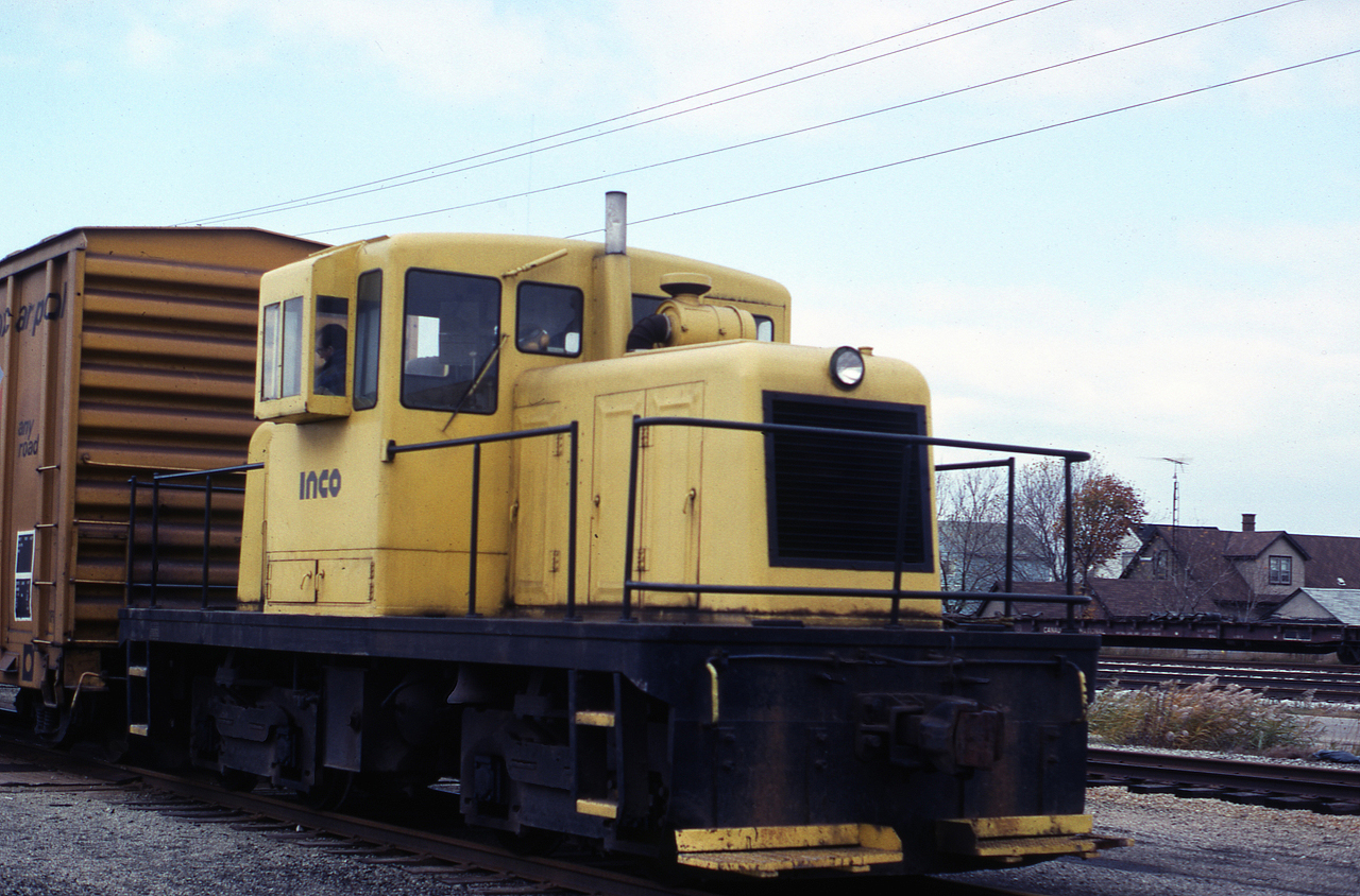 Doug Courtney provides us with this image of INCO's GE Center Cab outside the company gates, along Durham St near the weigh scale location.  The CN NICKEL yard is in the background with flat cars being stored.  The unit  displays the typical INCO Yellow paint scheme of the time period.  RAILBOX cars were common sights here, as were Western Maryland Boxcars.  The locomotive remains on the property today, and is used infrequently to bring tank cars into the facility. It is the last of the GE Center Cabs in Port Colborne having been on site for over 70 years.