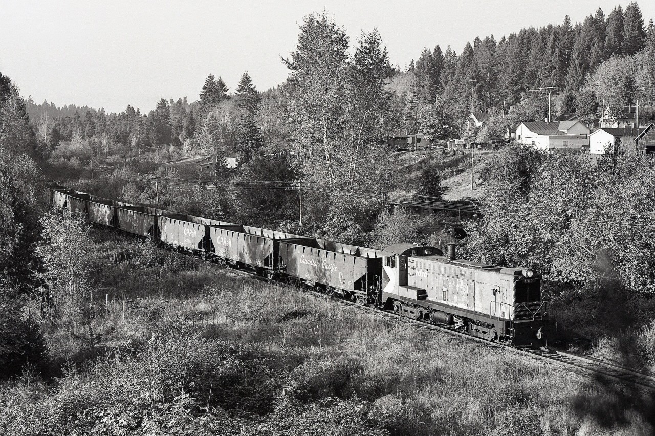On Vancouver Island, CP’s E&N Wellcox yard in Nanaimo was the primary rail-barge connection from the mainland, and was served by three roadswitcher assignments for full coverage every day.  As a relieving mechanical chargehand there, I was well placed to be aware of unusual movements, and on Thursday 1980-10-16, the afternoon roadswitcher assignment with Baldwin DS4-4-1000 number 7070 was tasked to deliver a string of empty ballast cars to the Fiddicks gravel pit for reloading, a rare opportunity to catch that unit outside yard limits.  By climbing a rather uncooperative tree just north of the South Wellington flagstop, a good camera perch was obtained, and precisely at 1700 PDT, I was rewarded with Work Extra 7070 heading south.  As a particular delight, the lighting was perfect for highlighting the front “thumb-up” Sharon coupler, BLW part number 37-B-880.