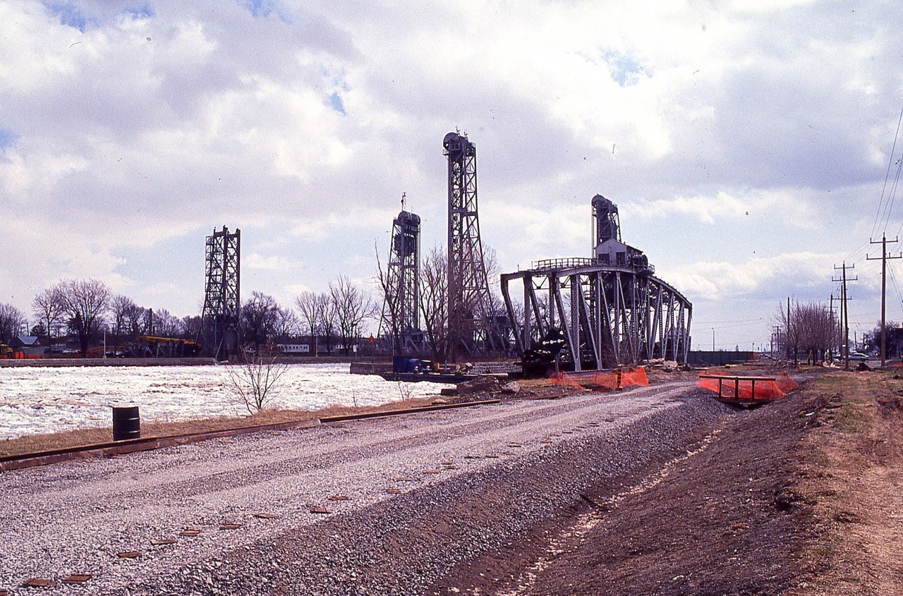 At the time of this photo, Trillium was known as the Port Colborne Harbour Railway; now currently known as 'GIO'.
I had been looking at Glenn Cherry's posting along Harbour Spur with #1859 from a few years ago (id=27715) and so am offering up this.....
 CN has removed Bridge 20, (in background) which isolated the elevator buildings down by Lake Erie as the CN Humberstone link has been severed. The new connection is under construction running along the west side of the canal, as seen here; and PCHR would be the operator of record once they had their Grand Opening Ceremonies on July 2, 1997.
When this image was taken, the track had only been laid as far as the Sherwood Forest road crossing.