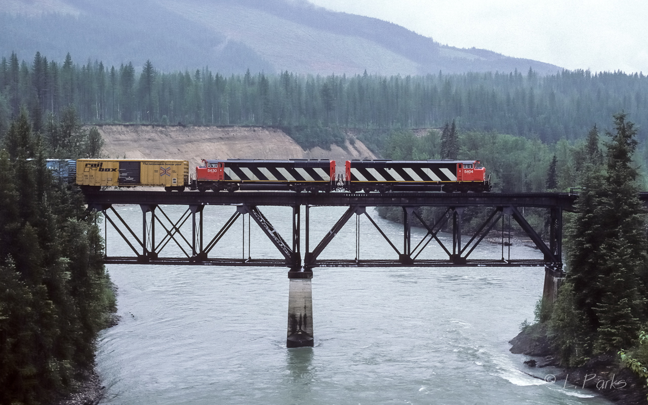 First day of summer holidays and on the lookout to catch those somewhat new SD60's in action. Trouble is, it's pouring rain and I'm standing with my coat over my head as the train passes over a bridge right next to the McMurphy rest area.