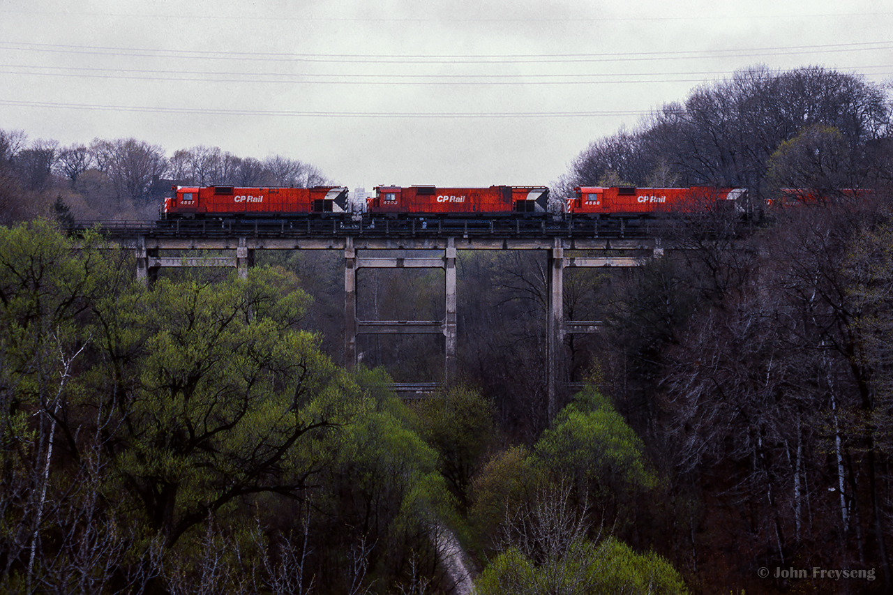 A rainy spring day finds four of CP's 6-axle MLW fleet handling an extra slag train west through Toronto's Summerhill neighbourhood. Per Ron Bowman, slag from the Sudbury area was being laid as ballast along the Galt and Windsor subs in 1979, replacing the old stone ballast in the process.

The train is seen crossing over the former Toronto Belt Line railway. Begun by the Toronto Belt Land Corporation in 1890, the project would be completed by the Grand Trunk Railway in 1892. Low ridership resulted in passenger service ending in 1894 after only two years of service, and the stretch seen here from Rosedale to to Moore Avenue being abandoned. The remainder of the line would see local freight service while being abandoned in stages into the 1970s.

Scan and editing by Jacob Patterson.